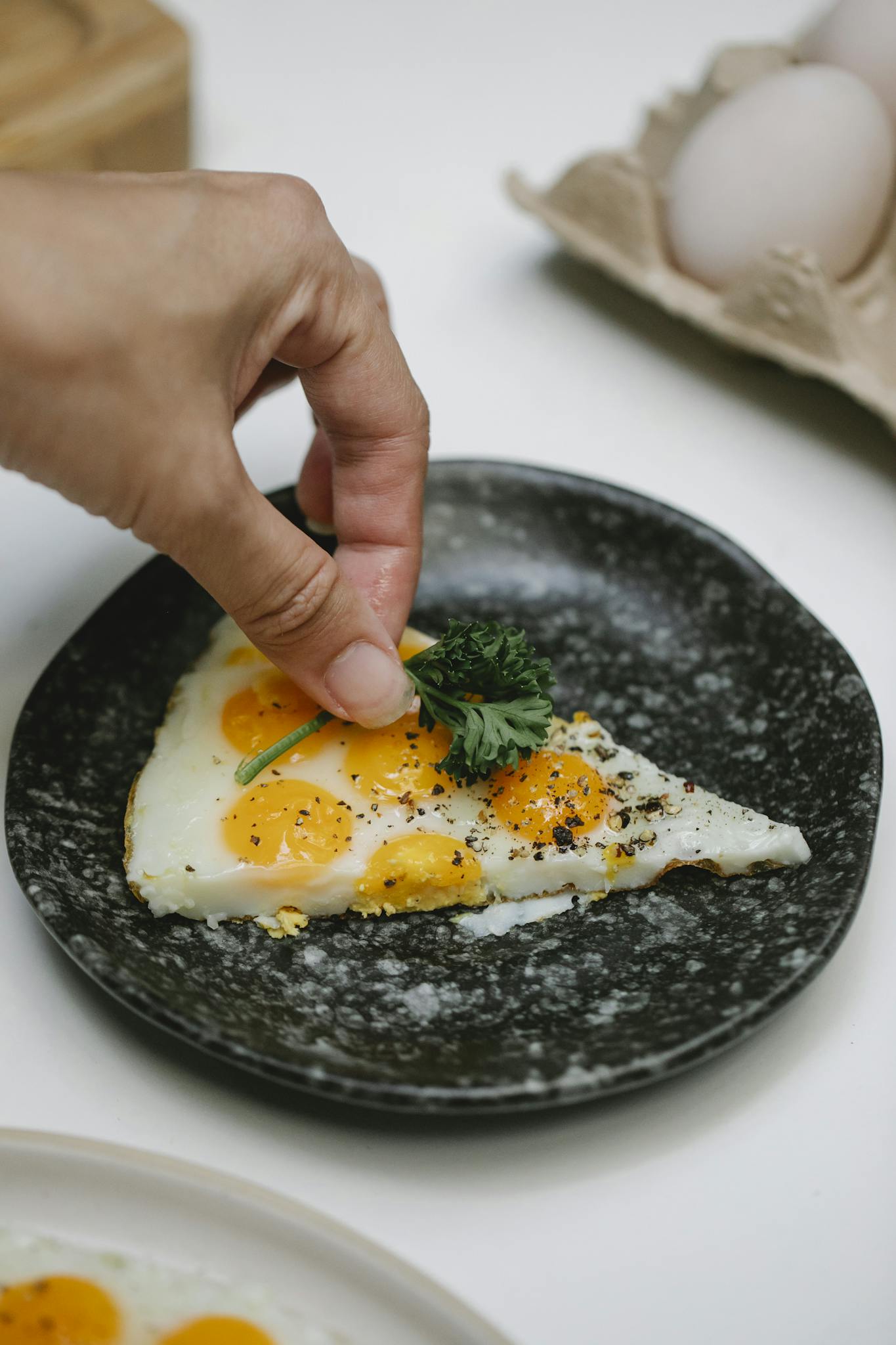 Chef adding sprig of parsley on fried eggs