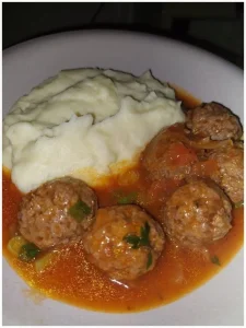 Fleischbällchen in Tomatensauce serviert mit Kartoffelpüree