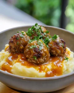 Hackbällchen in cremiger Sauce serviert mit Kartoffelpüree auf einem Teller.