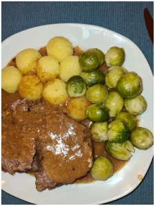 Rinderbraten mit Kartoffelklößen und Rosenkohl auf einem Teller