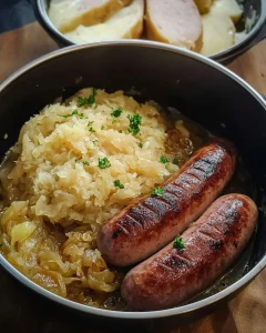 Schäufele mit Sauerkraut und Leberwürstle auf einem weißen Teller serviert