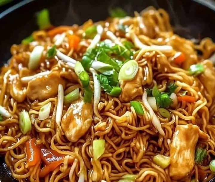 Wok-Nudeln mit Hähnchen und frischen Sojasprossen in einem bunten Wok-Gericht.