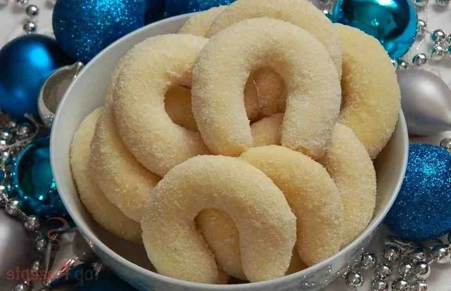 Kokos Sahnekipferl auf einem Teller mit dekorativen Kokosraspeln