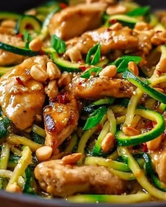 Erdnuss-Hähnchen mit Zucchininudeln auf einem Teller serviert