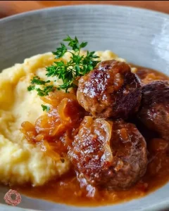 Frikadellen mit Zwiebelsauce und Kartoffelpüree auf einem Teller serviert.