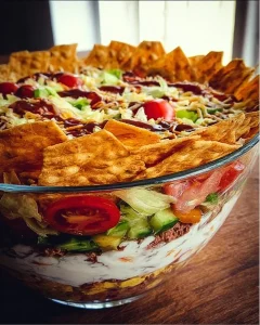 Bunter Taco-Schichtsalat mit frischen Zutaten, serviert in einer Schüssel.