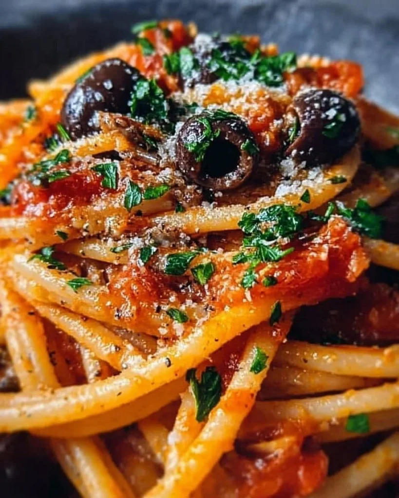 Delicious Puttanesca-Pasta mit Sardellen auf einem Teller angerichtet.