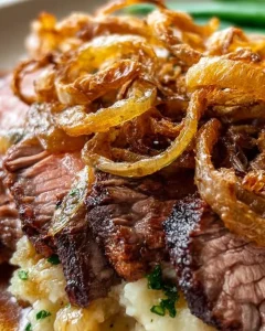Zwiebelrostbraten mit saftigem Rindfleisch und goldbraunen Zwiebeln serviert