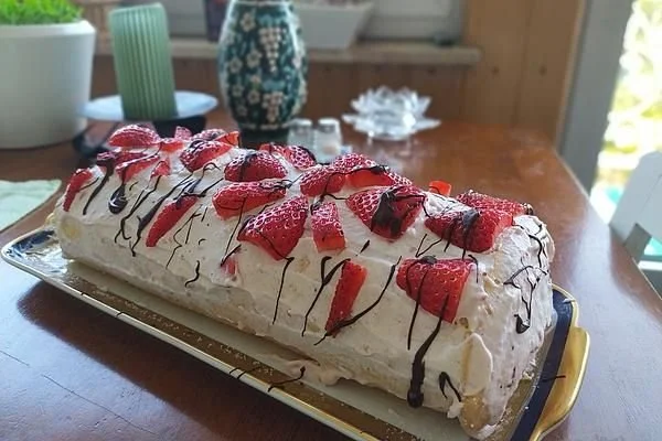 Deliziosa Biskuitrolle mit frischer Erdbeerfüllung auf einem Teller