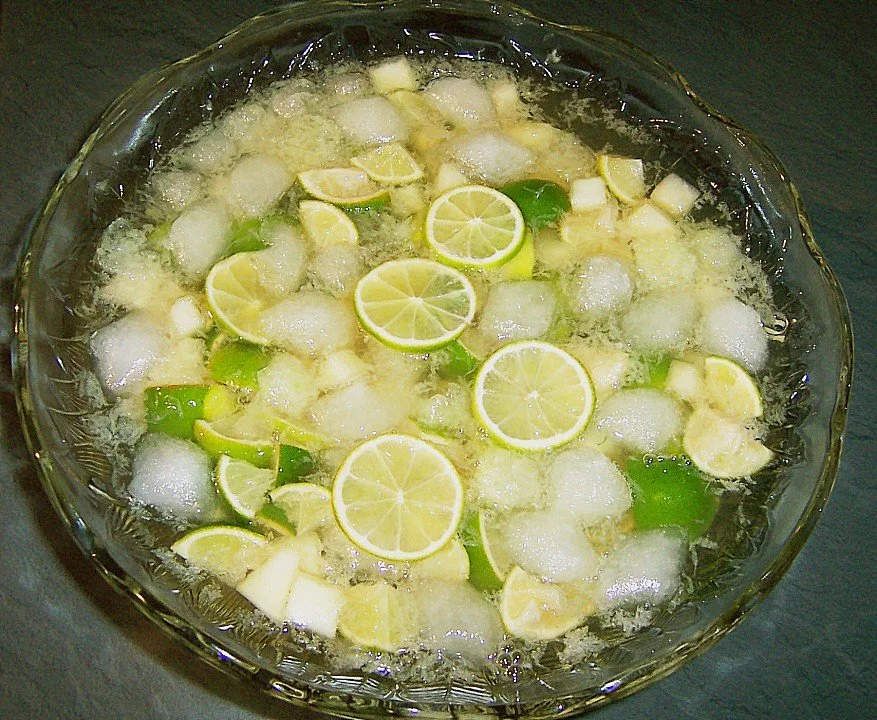 Erfrischender Caipirinha-Punsch in einem Glas mit Limetten und Zuckerstückchen.