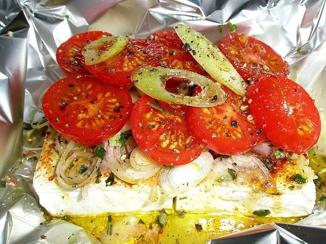 Leckeres Gericht mit gebackenem Schafskäse, serviert mit frischen Kräutern und Gemüse