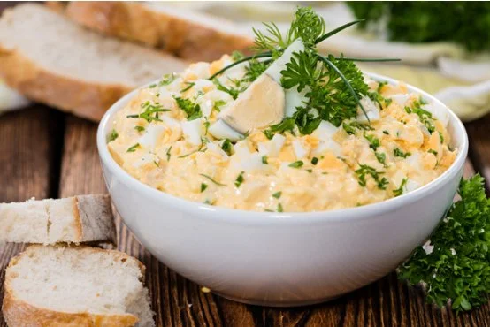 Klassischer Eiersalat in einer Schüssel mit frischen Kräutern garniert