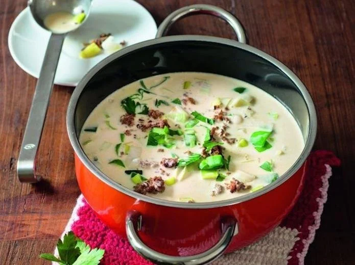 Schüssel mit Lauch-Hackfleisch-Suppe, garniert mit frischen Kräutern.