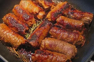 Mini-Rouladen mit Pesto-Schinken-Füllung und Oliven-Rotwein-Sauce auf einem Teller