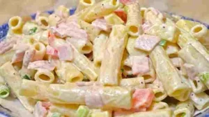 Nudelsalat mit Schinken und Käse in einer bunten Schüssel serviert