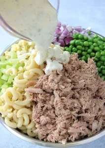 Nudelsalat mit Thunfisch auf einem Teller, garniert mit frischen Kräutern.