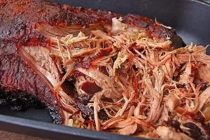 Zartes pulled pork auf einem Brötchen, serviert mit BBQ-Sauce und Krautsalat.