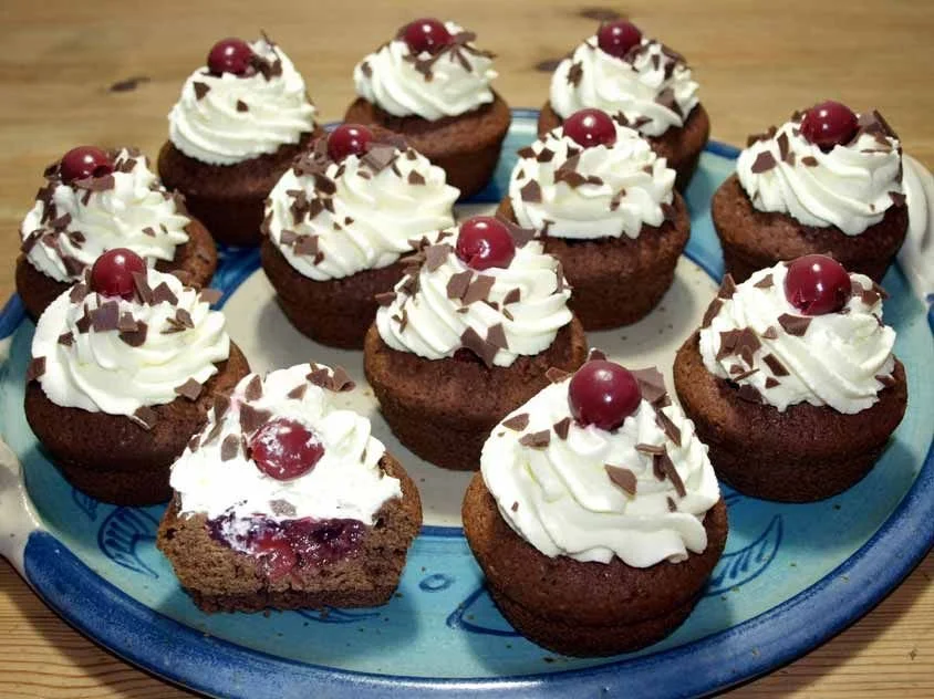 Schwarzwälder Kirsch-Muffins mit Sahne und Kirschen, appetitlich angerichtet