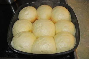 Ein Teller süße Dampfnudeln, frisch gebacken und mit Puderzucker bestäubt.